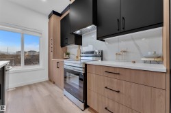 Modern kitchen featuring black upper cabinetry, wood-finish lower cabinetry, and quartz countertops - 