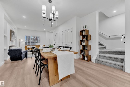 Dining area featuring a contemporary chandelier, wood-finish flooring, and crisp white walls - 269 Falcon Crescent, Leduc, AB - Indoor Photo Showing Dining Room