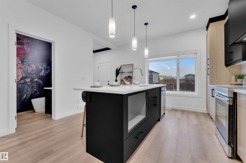 Kitchen featuring a contrasting black and light wood cabinetry, a center island with a white countertop and integrated sink, stainless steel appliances, and pendant lighting - 269 Falcon Crescent, Leduc, AB - Indoor Photo Showing Kitchen With Upgraded Kitchen