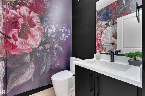 Powder room featuring a floral accent wall, a modern vanity with a white countertop, and a contemporary black faucet - 269 Falcon Crescent, Leduc, AB - Indoor Photo Showing Bathroom