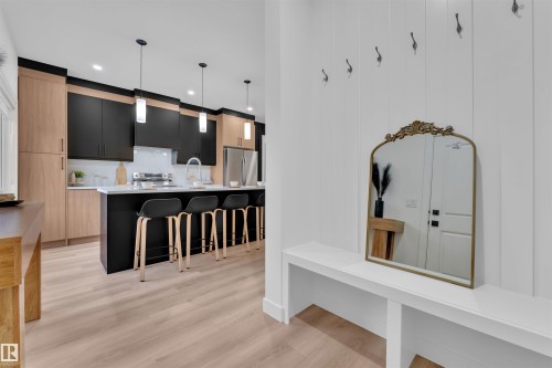 Modern kitchen featuring a black center island with a white countertop, light wood-finish flooring, two-tone cabinetry, and stainless steel appliances - 269 Falcon Crescent, Leduc, AB - Indoor Photo Showing Kitchen