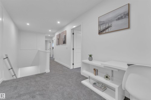 Bright hallway featuring recessed lighting, a built-in white desk with shelving, light gray carpeting, crisp white walls, and dark hardware on interior doors - 269 Falcon Crescent, Leduc, AB - Indoor