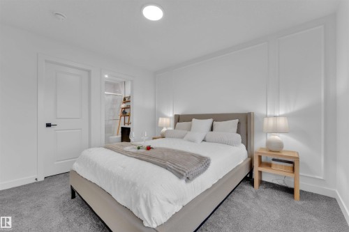Carpeted bedroom featuring white walls with decorative molding, a recessed ceiling light, and a modern paneled door with black hardware - 269 Falcon Crescent, Leduc, AB - Indoor Photo Showing Bedroom