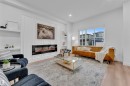 Living area featuring a sleek linear fireplace with a white paneled accent wall, light wood-finish flooring, recessed lighting, and built-in shelving - 269 Falcon Crescent, Leduc, AB  - Indoor Photo Showing Living Room With Fireplace 