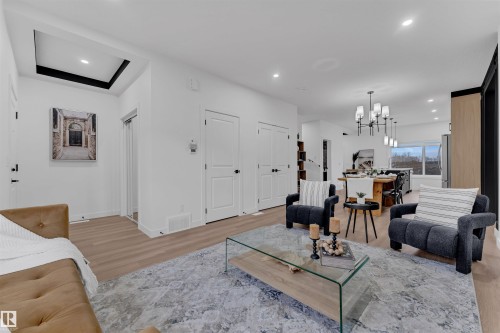 Open-concept living area featuring light wood-finish flooring, recessed lighting, and a tray ceiling accent - 269 Falcon Crescent, Leduc, AB - Indoor Photo Showing Living Room
