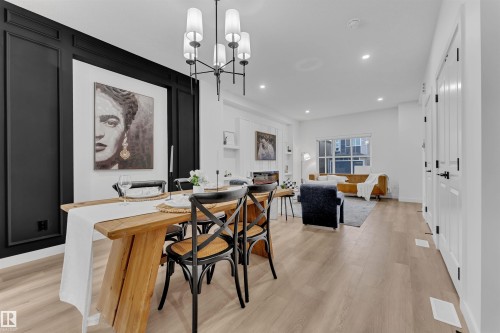Dining area featuring a contemporary chandelier, light wood-finish flooring, recessed lighting, and a prominent accent wall with black panel molding - 269 Falcon Crescent, Leduc, AB - Indoor Photo Showing Dining Room