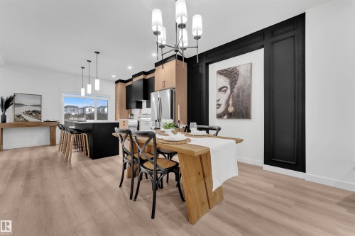 Open-concept dining and kitchen area featuring wood-finish flooring, a modern chandelier, and a black accent wall with decorative paneling - 269 Falcon Crescent, Leduc, AB - Indoor Photo Showing Other Room