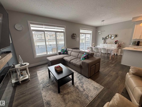 Open-concept living area featuring wood-finish flooring, large windows, and a sliding glass door - 1440 Darby Green, Edmonton, AB - Indoor Photo Showing Living Room