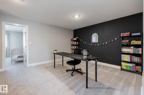 Spacious room featuring light gray walls, a contrasting black accent wall, and a light-colored carpeted floor - 1440 Darby Green, Edmonton, AB - Indoor Photo Showing Office