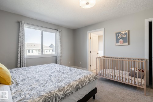 Bedroom featuring light gray wall paint, a large window, a ceiling-mounted light fixture, and textured carpeting - 1440 Darby Green, Edmonton, AB - Indoor Photo Showing Bedroom