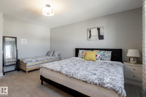 Carpeted room featuring light gray walls, a flush-mount ceiling light fixture, and a window with patterned curtains - 1440 Darby Green, Edmonton, AB - Indoor Photo Showing Bedroom