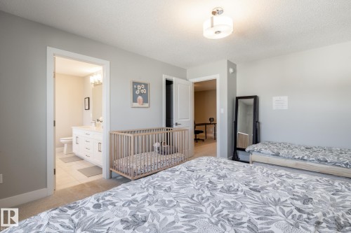 Spacious bedroom featuring light gray walls, carpet flooring, and a modern ceiling light fixture - 1440 Darby Green, Edmonton, AB - Indoor Photo Showing Bedroom