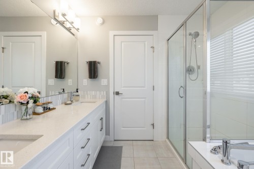 Bathroom featuring a dual vanity with light-colored countertops, white cabinetry, and brushed nickel pull handles - 1440 Darby Green, Edmonton, AB - Indoor Photo Showing Bathroom