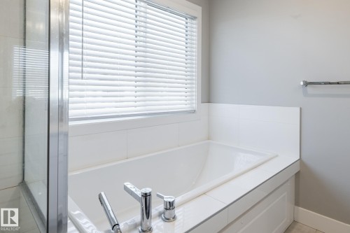 Soaking tub with integrated faucet, white tile surround, and privacy blinds - 1440 Darby Green, Edmonton, AB - Indoor Photo Showing Bathroom