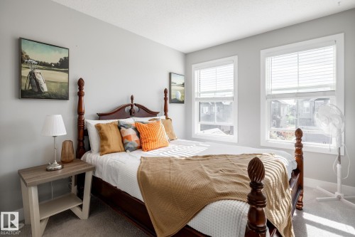 Carpeted bedroom featuring two large windows with horizontal blinds, light gray wall paint, and white trim - 1440 Darby Green, Edmonton, AB - Indoor Photo Showing Bedroom