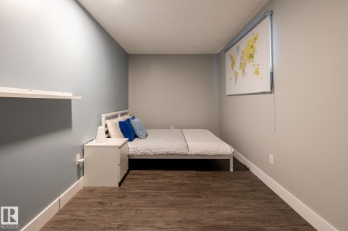 Bedroom featuring wood-finish flooring, two-tone wall paint, white baseboards, and a built-in wall shelf - 1440 Darby Green, Edmonton, AB - Indoor Photo Showing Bedroom
