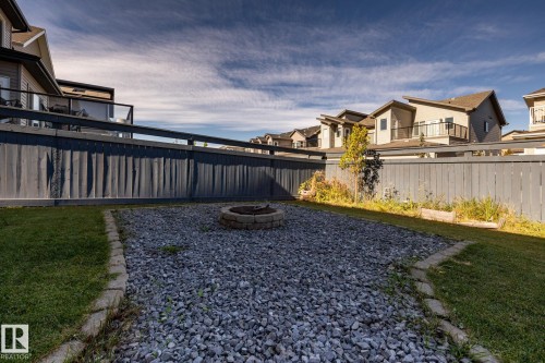 Expansive backyard featuring a gravel fire pit area, manicured lawn, and natural wood fencing - 1440 Darby Green, Edmonton, AB - Outdoor