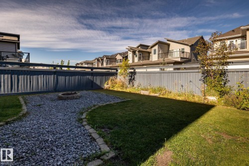 Landscaped backyard featuring a gravel fire pit area, manicured lawn, and perimeter fencing - 1440 Darby Green, Edmonton, AB - Outdoor