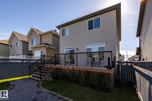 Rear exterior with a wood deck featuring black metal railings and steps to the gravel path - 1440 Darby Green, Edmonton, AB - Outdoor With Deck Patio Veranda