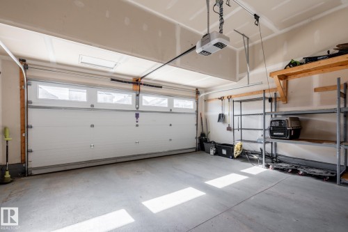 Spacious garage featuring a white overhead door with upper-row windows, a concrete floor, and an automatic garage door opener - 1440 Darby Green, Edmonton, AB - Indoor Photo Showing Garage