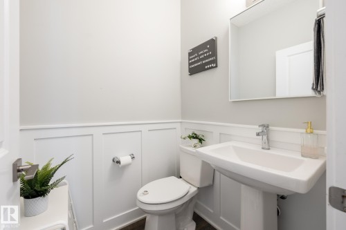 Powder room with wainscoting, pedestal sink, chrome fixtures, and a wall-mounted mirror - 1440 Darby Green, Edmonton, AB - Indoor Photo Showing Bathroom