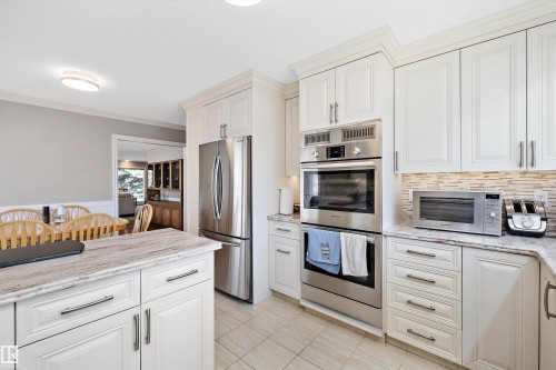 Kitchen featuring white cabinetry, built-in stainless steel appliances, and a marble-finish countertop island - 227 Westridge Road, Edmonton, AB - Indoor Photo Showing Kitchen