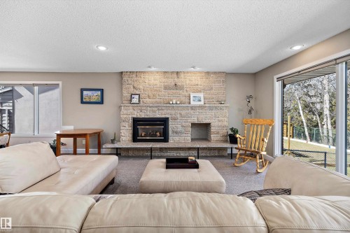 Stone-faced fireplace with hearth seating, recessed lighting, and large windows - 227 Westridge Road, Edmonton, AB - Indoor Photo Showing Living Room With Fireplace