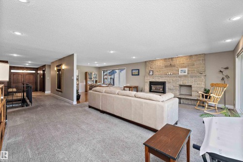 Spacious living area featuring a stone fireplace, recessed lighting, and soft carpet flooring - 227 Westridge Road, Edmonton, AB - Indoor Photo Showing Other Room With Fireplace