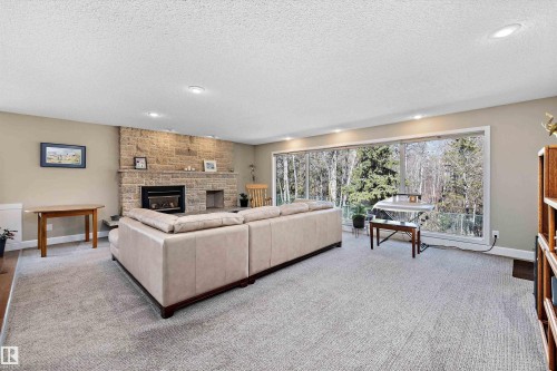 Spacious living area featuring a full-wall window, stone-clad fireplace with hearth, and recessed lighting - 227 Westridge Road, Edmonton, AB - Indoor Photo Showing Living Room With Fireplace