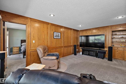 Carpeted living area featuring wood paneled walls, recessed lighting, and a built-in entertainment center with shelving and storage - 227 Westridge Road, Edmonton, AB - Indoor