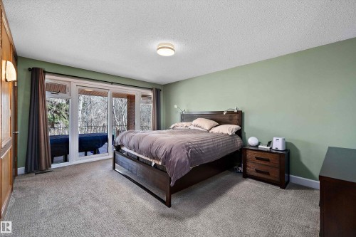 Sliding glass doors opening to an outdoor area, complemented by light green walls and textured carpeting - 227 Westridge Road, Edmonton, AB - Indoor Photo Showing Bedroom