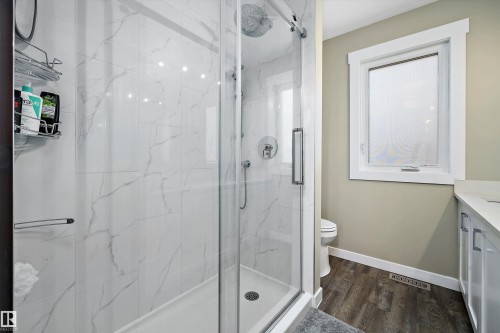 Glass-enclosed shower featuring white-veined tile walls, a rain showerhead, and a handheld shower attachment - 227 Westridge Road, Edmonton, AB - Indoor Photo Showing Bathroom
