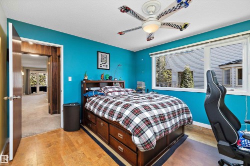 Light wood-finish flooring with a dark accent strip, bright blue walls, and a multi-pane window with white trim - 227 Westridge Road, Edmonton, AB - Indoor Photo Showing Bedroom