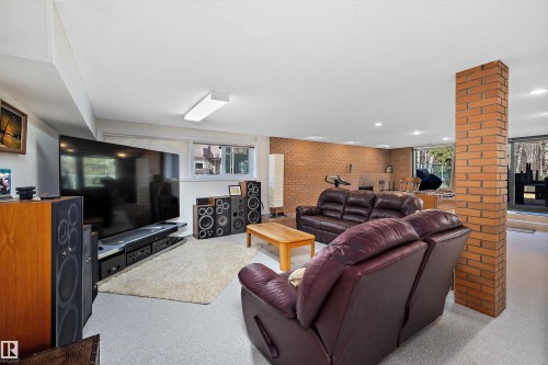 Spacious entertainment room featuring brick accent walls, a brick support column, and light-colored carpeting - 227 Westridge Road, Edmonton, AB - Indoor
