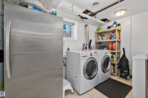 Dedicated laundry area featuring a front-loading washer and dryer, adjacent to a stainless steel refrigerator - 227 Westridge Road, Edmonton, AB - Indoor Photo Showing Laundry Room