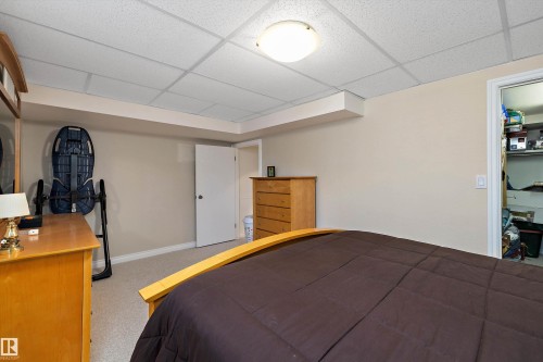 Carpeted room featuring a white paneled door, a neutral wall color, and a dropped ceiling with recessed lighting - 227 Westridge Road, Edmonton, AB - Indoor Photo Showing Bedroom