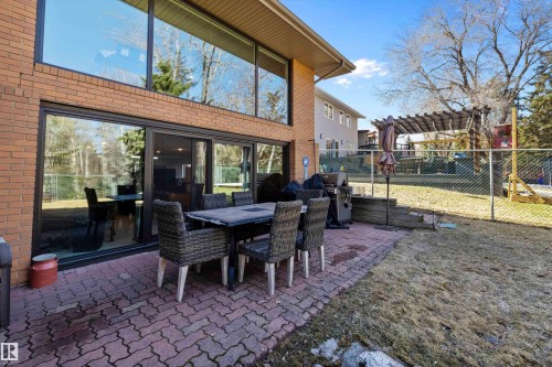 Brick exterior with expansive glass window walls, a ground-level sliding glass door system, and a paver patio - 227 Westridge Road, Edmonton, AB - Outdoor With Deck Patio Veranda With Exterior