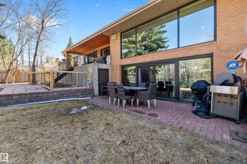 Brick exterior residence featuring expansive black-framed windows and a lower-level sliding glass door system - 227 Westridge Road, Edmonton, AB - Outdoor With Deck Patio Veranda