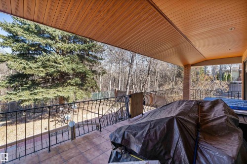 Spacious covered patio with terracotta-hued tile flooring, black wrought iron railing, and a slatted ceiling - 227 Westridge Road, Edmonton, AB - Outdoor With Deck Patio Veranda With Exterior