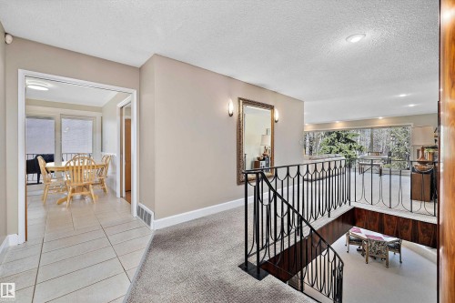 Interior landing with wrought iron railing staircase, carpeted flooring, and a large wall mirror with sconce lighting - 227 Westridge Road, Edmonton, AB - Indoor Photo Showing Other Room