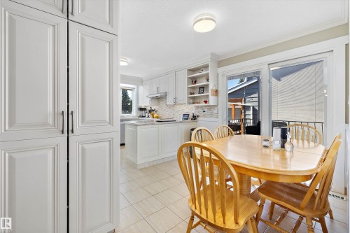 Kitchen and dining area featuring white cabinetry, tile flooring, and a sliding glass door to an outdoor space - 227 Westridge Road, Edmonton, AB - Indoor Photo Showing Dining Room