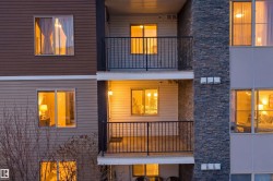Multi-level exterior featuring balconies with black railings, horizontal siding in varying shades, and a stone facade column - 