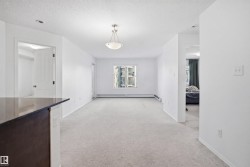 Expansive living area featuring light carpeting and white walls - 