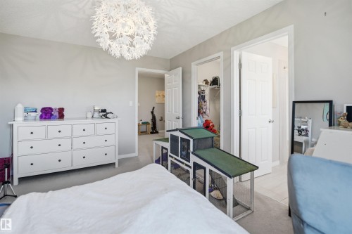 Recessed window with light-filtering curtains, overhead decorative light fixture, built-in desk with hinged top, and neutral wall paint - 7323 24 Ave, Edmonton, AB - Indoor Photo Showing Bedroom