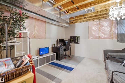 Unfinished basement space featuring exposed ceiling joists, partially finished drywall, and a contemporary pendant light fixture - 7323 24 Ave, Edmonton, AB - Indoor Photo Showing Basement
