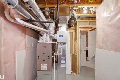 Mechanical room featuring a water heater, exposed ductwork, and electrical panel - 7323 24 Ave, Edmonton, AB - Indoor Photo Showing Basement