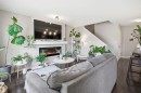 Living area featuring dark wood-finish flooring, light grey walls, and a contemporary fireplace with a white mantel - 7323 24 Ave, Edmonton, AB  - Indoor Photo Showing Living Room With Fireplace 