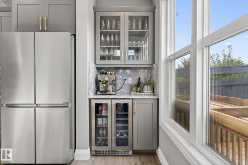Built-in beverage station featuring a dual-zone wine cooler, glass-front cabinetry, and a marble-finish backsplash - 1737 Dumont Crescent, Edmonton, AB - Indoor Photo Showing Other Room