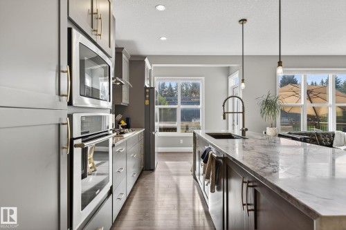 Modern kitchen featuring an expansive island with a waterfall edge countertop, built-in sink, and pendant lighting - 1737 Dumont Crescent, Edmonton, AB - Indoor Photo Showing Kitchen
