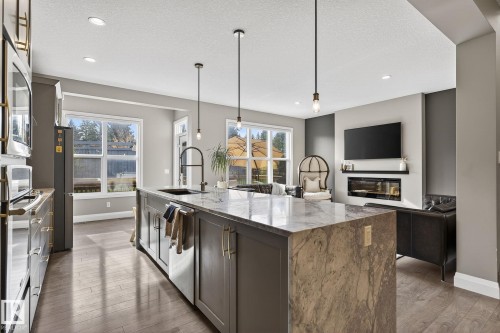 Open-concept kitchen and living area featuring a large island with a waterfall countertop, integrated sink, and pendant lighting - 1737 Dumont Crescent, Edmonton, AB - Indoor Photo Showing Kitchen With Upgraded Kitchen